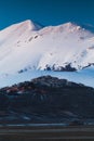 A view of Castelluccio di Norcia in front of a big snowed mountaind and reflected in a lake in the valley