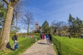 View of Central Park in New York, featuring people enjoying sunny day on pathway that leads to striking historic tower. Royalty Free Stock Photo