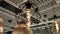 View of a chandelier with a glass lamp with a luminous spiral inside in a metal frame made of polyhedrons in a store.