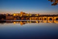 View on Charles Bridge and Prague Castle over Vltava River during early night with wonderful blue sky and yellow city Royalty Free Stock Photo