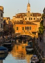 View of a charming canal with boats docked and big green tree in Venice, Italy