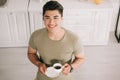 View of cheerful asian man holding coffee cup while smiling at camera Royalty Free Stock Photo