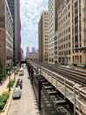 View of Chicago Loop on Wabash Ave, where el tracks cast patterns onto street below, and clouds cover the sky while train Royalty Free Stock Photo