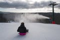 Children on a bobsleigh ride downhill past a snow maker Royalty Free Stock Photo