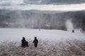 Children on a bobsleigh ride downhill past a snow maker Royalty Free Stock Photo