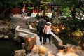 A view of a Chinese middle aged couple walking on a small bridge