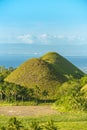 View of Chocolate Hills in Bohol. Base flanked by coconut trees and fields of green. Mid afternoon shot with Cebu in far Royalty Free Stock Photo