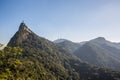 View of Christ the Redeemer on top of Mount Corcovado in daytime with blue sky overhead & forest surrounding it in Rio de Janeiro