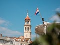 View of the christian church belltower in the small town of Sutivan on the island of brac. Croatian flag from a nearby boat in the Royalty Free Stock Photo