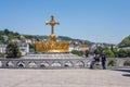 View on the Christian cross and an elderly disabled pilgrim along with volunteer in the Sanctuary of Our Lady of Lourdes, July 9,