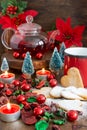 View of Christmas decoration with red mug, rooibos tea in glass teapot, gingerbread cookies and candles