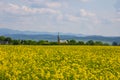 View of the church on the background of a yellow rapeseed field, blue sky and mountains Royalty Free Stock Photo