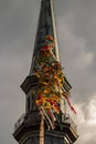 View of a church tower in the background with a maypole in the foreground