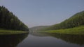 View of chusovaya river from sailing catamaran. POV. Green bacnk of river on both sides.