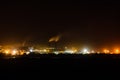 View on city lights at night. Smoke from chimneys of the factory rises to sky. Environmental pollution concept Royalty Free Stock Photo