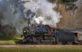 View of a Classic Steam Passenger Train, Blowing Lots of Smoke and Steam, While Traveling