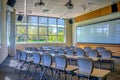 A view of a classroom equipped with a projector screen, with rows of chairs neatly arranged, A lush, modern empty classroom with Royalty Free Stock Photo