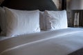 Angled view of a cleanly made hotel bed, with fresh white and gray bedding and a black headboard