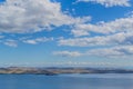 View of clear calm undulating blue water of Lake Baikal, mountains on the horizon, blue cky, white clouds