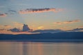 view of the clear calm undulating blue water of Lake Baikal, mountains on horizon, sunset yellow, pink light, clouds