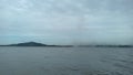 The view of a clear sky and a hill from atop a ship in the middle of the sea