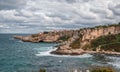 View of cliffs dropping into the ocean as water swirls around the rugged rocky coastline. Rock Formations coast Against Sky.