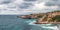 View of cliffs dropping into the ocean as water swirls around the rugged rocky coastline. Rock Formations coast Against Sky.