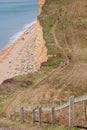 View from clifftop at a golden beach with people enjoying walking and coastline of West Bay Royalty Free Stock Photo