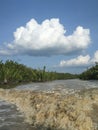 View of clouds and rivers in a swampy area with brown water.
