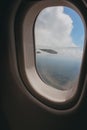 View of clouds and a wing of an airplane seen through from a glass window