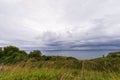 View of cloudy blue sky, green field and sea in the background, Royalty Free Stock Photo