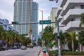 View of Collins Avenue with passing cars at the intersection of 43rd Street in Miami Beach against the backdrop of buildings.