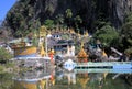 View on colorful kitschy temple with golden towers reflecting in a lake against steep mountain face and bridge