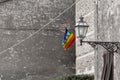 View of colorful Peace flag on old stone wall with street lamp in the Volterra, Italy