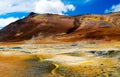 View on colorful valley with yellow sulfur deposits in volcanic barren dry landscape with red mountains background