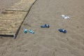 View of colorfull shoes left by tourists on sand beach near wooden path.