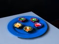 A view of 5 Colourful lit diyas on a plate