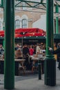 View through the columns of people at a cheese stand inside Borough Market, London, UK