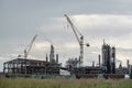 View of a complex of industrial buildings with smoking chimneys and construction cranes