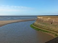 View of the concrete seawall in the cliffs area blackpool with the beach and incoming tide in sunlight with the outs wall of the