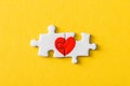 View of connected jigsaw puzzle pieces with drawn red heart isolated on yellow