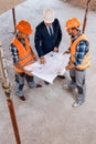 View of constructors and businessman holding blueprint