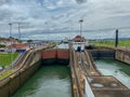 A view of a container ship and two yachts entering the first lock in the Panama Canal from a much lower cruise ship Royalty Free Stock Photo