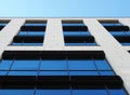 View of the corner of a white modern office building with blue sky reflected in large glass windows Royalty Free Stock Photo