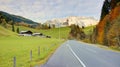 View of a country road passing by a farm land with a church on top of the hill and Mountain Hochkoenig Royalty Free Stock Photo