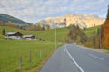 View of a country road passing by a farm land with a church on top of the hill and Mountain Hochkoenig Royalty Free Stock Photo