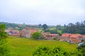 View of countryside of Santillana del Mar, Cantabria, Spain. Green farmland with trees, small houses and church