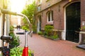 View couple in love walking on a narrow street in Amsterdam. Historical, traditional and typical buildings and many plants are in Royalty Free Stock Photo