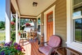 View of cozy covered porch with chairs and flower pots