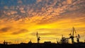 View of cranes at a harbour and bright golden sunset lighting the sky Royalty Free Stock Photo